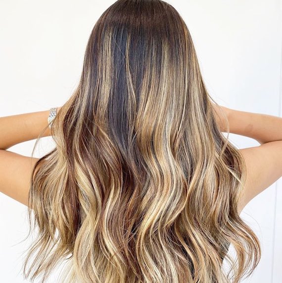 Back of woman’s head with long, wavy, tousled, beach blonde hair, created using Wella Professionals.