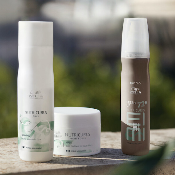 NutriCurls Shampoo, Mask and Fresh Up spray on a concrete surface.
