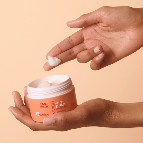 Hand schöpft INVIGO Nutri-Enrich Deep Nourishing Mask aus dem Topf.