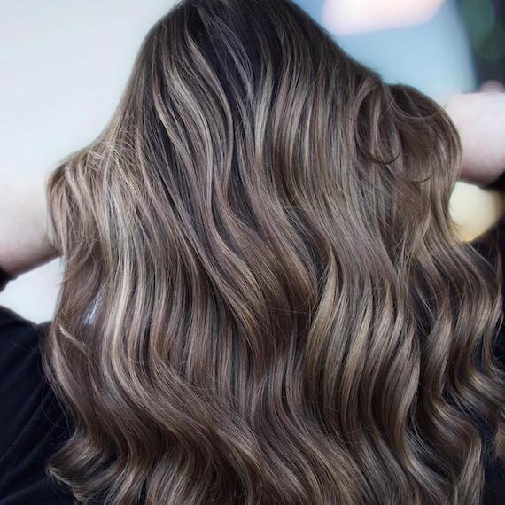 Back of woman’s head with long, wavy, black/brown hair and blonde highlights, created using Wella Professionals.
