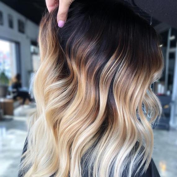 Side profile of woman with deep black roots and tousled blonde hair, created using Wella Professionals.