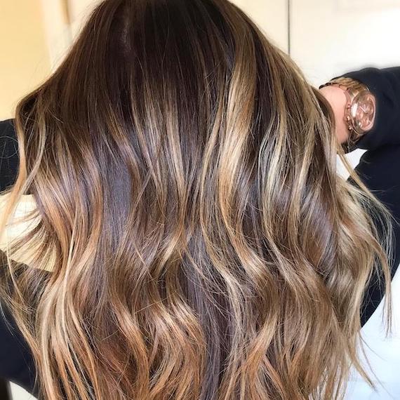 Hinterkopf einer Frau mit Balayage von Braun zu Goldblond, kreiert mit Wella Professionals.