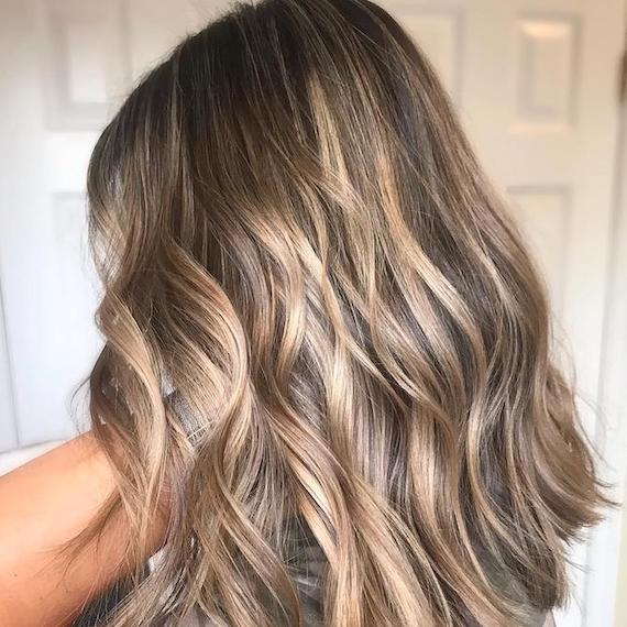 Blonde Strähnchen in dunklem, welligem Haar, kreiert mit Wella Professionals.