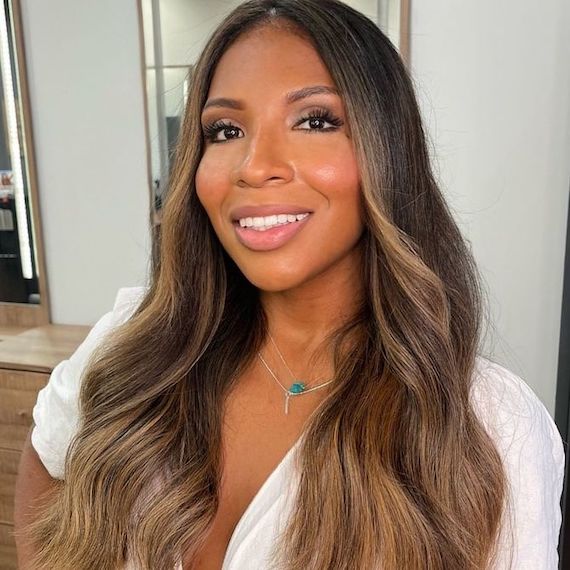 Headshot of a person with long brown hair and blonde ombre wearing white