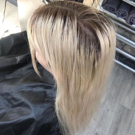 Foto von der Rückseite des Kopfes einer Frau mit blonden Haaren und dunklen Ansätzen.