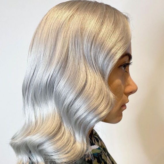 Seitenprofil einer Frau mit welligem weißblondem Haar, kreiert mit Wella Professionals.