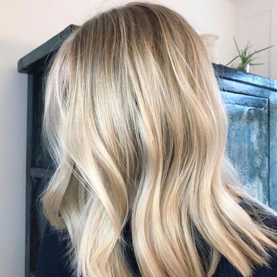 Seitenansicht einer Frau mit blonden, welligen Strandhaaren, gestylt mit Wella Professionals.