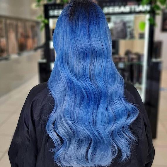 Back of woman’s head with long, wavy, bright blue hair, created using Wella Professionals.