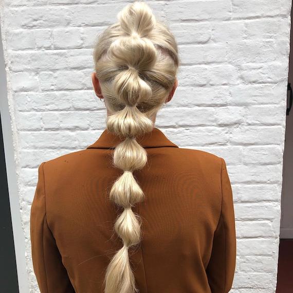 Hinterkopf der Frau mit langem, eisblondem Bubble Braid, kreiert mit Wella Professionals.