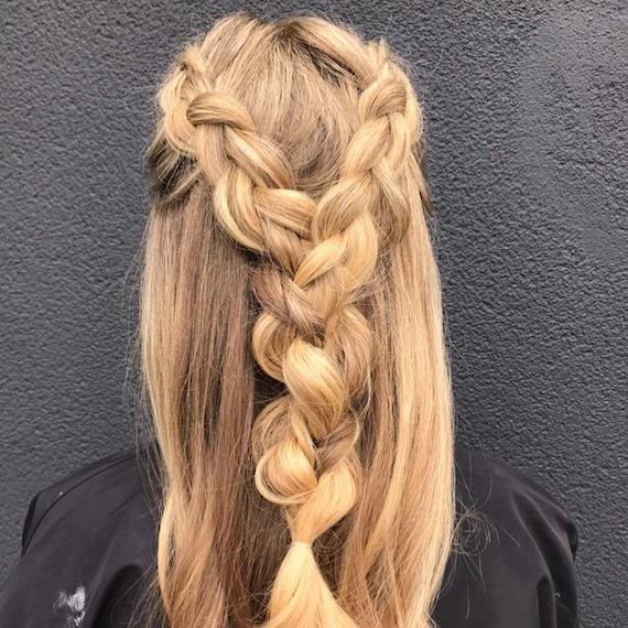 Hinterkopf einer Frau mit blondem, halb hochgezogenem holländischem Zopf, kreiert mit Wella Professionals.