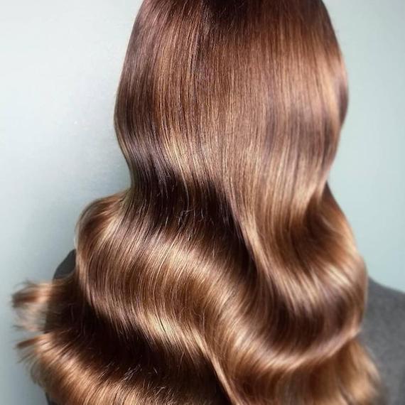 Hinterkopf einer Frau mit langem, gewelltem, kastanienbraunem Haar, kreiert mit Wella Professionals.