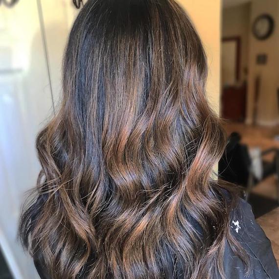 Hinterkopf einer Frau mit langem, gewelltem, mittelbraunem Haar, kreiert mit Wella Professionals.