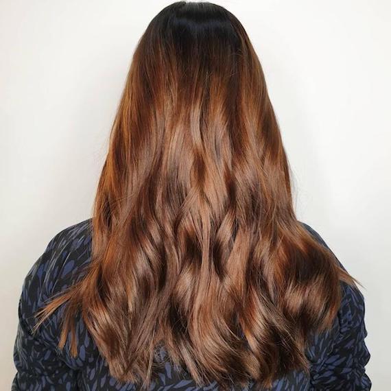 A person faces the wall so that their long, red-brown hair is on full show