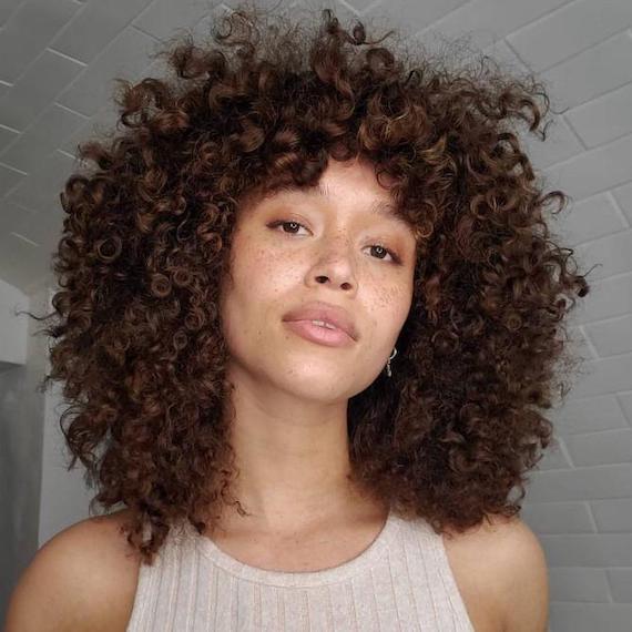 Der Kamera zugewandte Frau mit dunklen brünetten Locken, kreiert mit Wella Professionals.