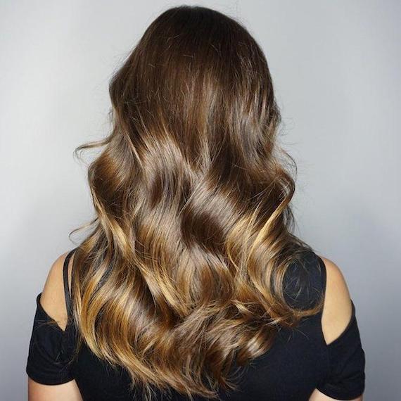 Foto vom Hinterkopf einer Frau mit langem, braunem Haar und karamellfarbener Balayage, kreiert mit Wella Professionals.