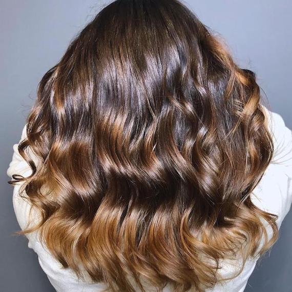 Foto vom Hinterkopf einer Frau mit langem, schokoladenbraunem Haar und Balayage, kreiert mit Wella Professionals.