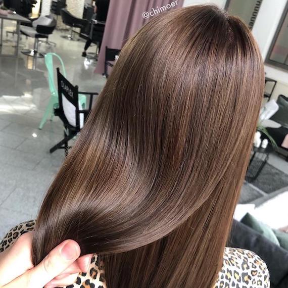 Back of woman’s head with long, straight, glossy brunette hair, created using Wella Professionals.
