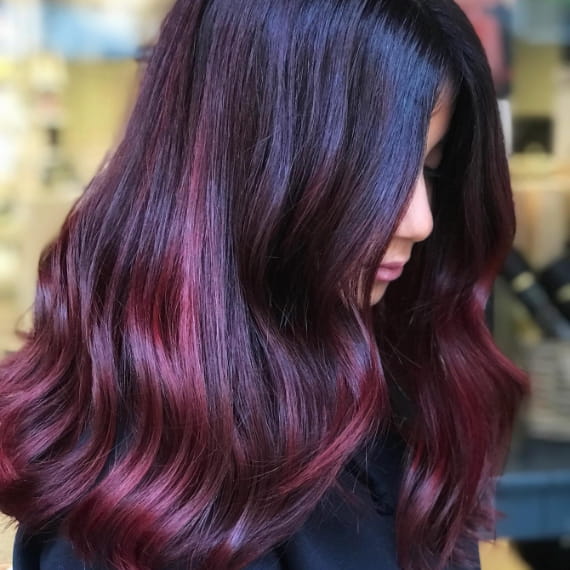 Woman with long burgundy balayage created with Wella Professionals
