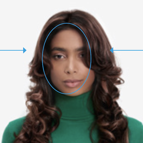Model with long, brown, loosely curled hair and caramel highlights looks directly into the camera.
