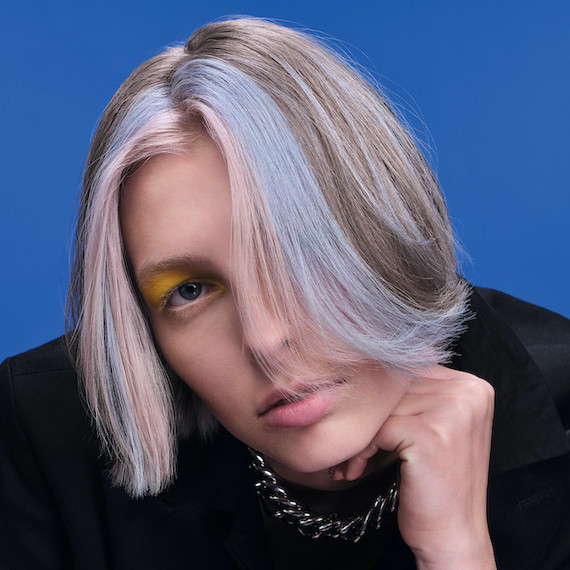Model with chin-length platinum blonde hair and sky blue, chunky highlights looks directly into the camera.