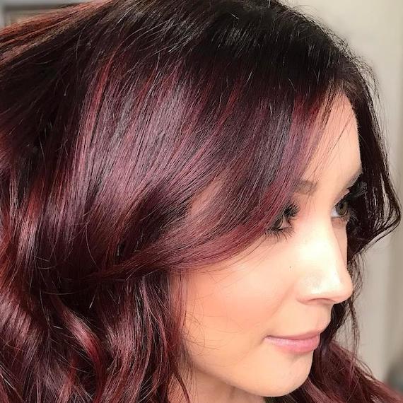 Foto einer Frau mit gewelltem, mahagonifarbenem Haar, kreiert mit Wella Professionals.