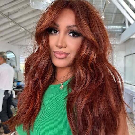 Model with long, tousled, bright copper hair hints of bronze through the face frame.