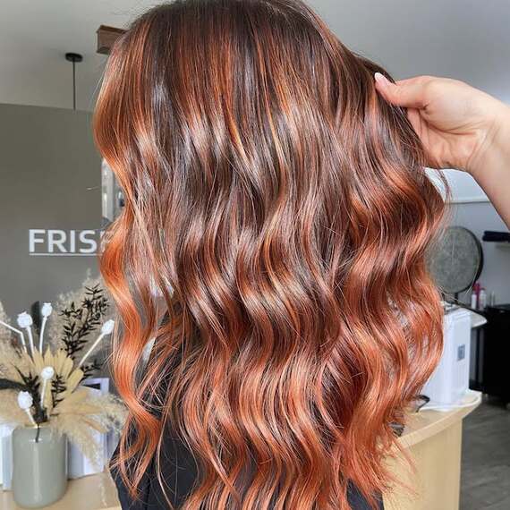 Model with long, tousled, brown hair featuring copper and bronze highlights.