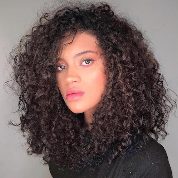 Woman with dark brown curly hair, cared for by Wella Professionals.
