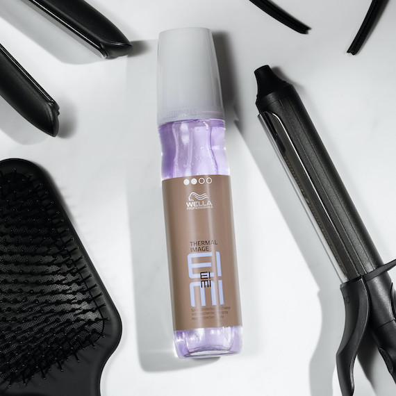 Das EIMI Thermal Image Hitzeschutzspray ist von beheizten Styling-Tools umgeben.