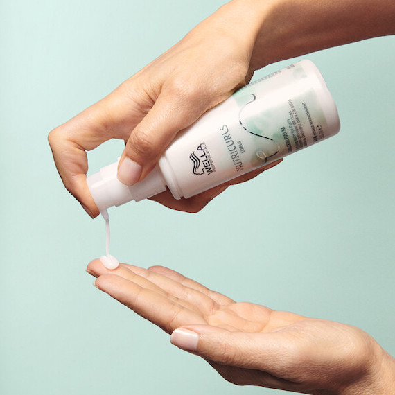 Model pumps out a drop of NutriCurls Curlixir Balm.