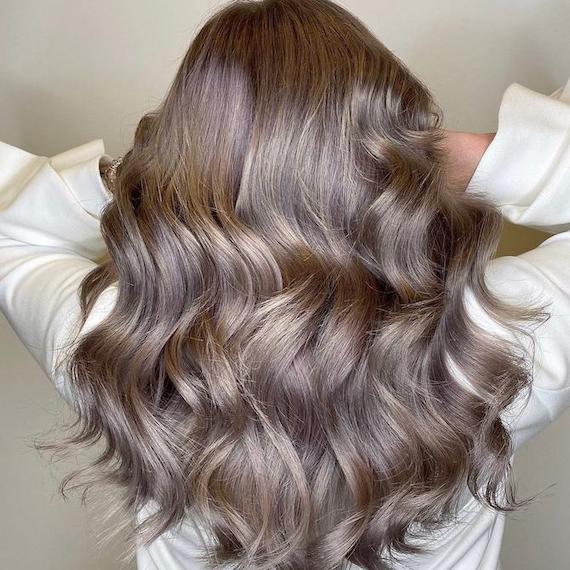 Back of woman’s head with long, loosely curled, dark ash blonde hair, created using Wel-la Professionals.