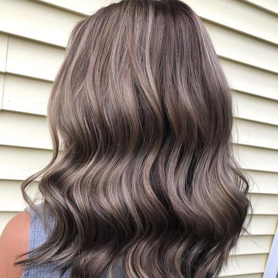 Back of woman’s head with long, wavy, brown hair and dark ash blonde highlights, creat-ed using Wella Professionals.