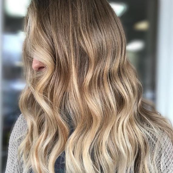 Seitenprofil eines Models mit dunkelblondem Haar, gestylt in langen lockeren Wellen. Kreiert von Wella Professionals.
