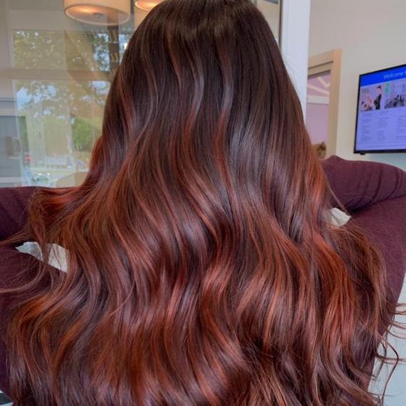 Foto vom Hinterkopf einer Frau mit langem, dunkelbraunem Haar mit roten Highlights, kreiert mit Wella Professionals.
