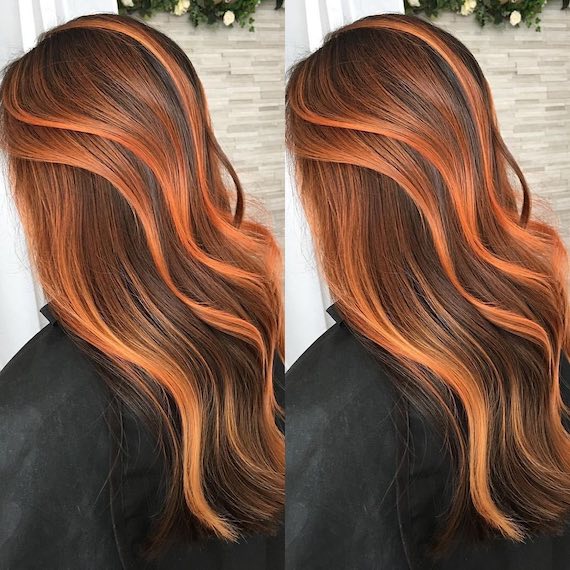 Back of model’s head. Their long, dark brown hair has been highlighted with chunky chili red highlights.