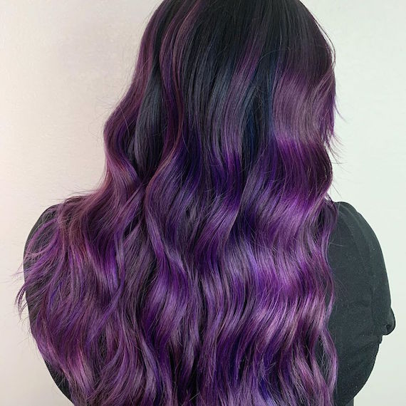 Back of woman’s head with long, wavy, dark purple hair, created using Wella Professionals.