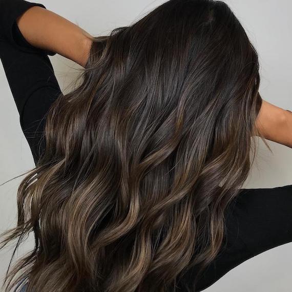 Back of woman’s head with wavy espresso hair colour and subtle balayage.