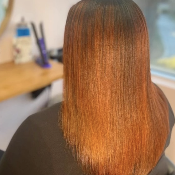 A person with long straight ginger brown hair faces away from the camera