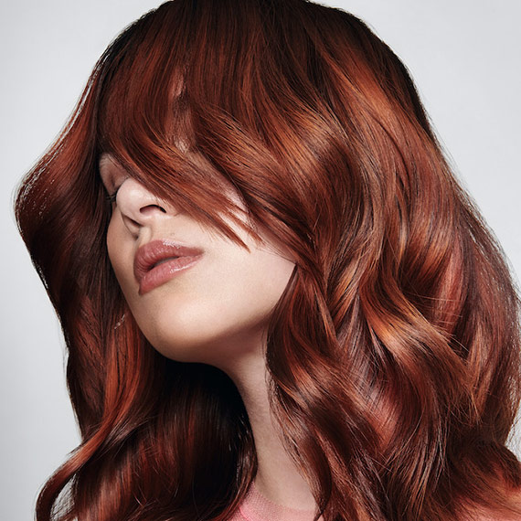 Model with long, loosely tousled, copper hair and a glass-like finish.