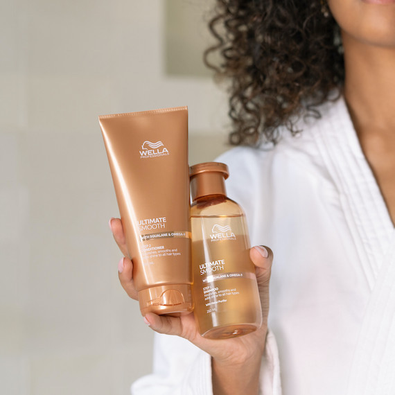 Model holds up ULTIMATE SMOOTH Conditioner and Shampoo.