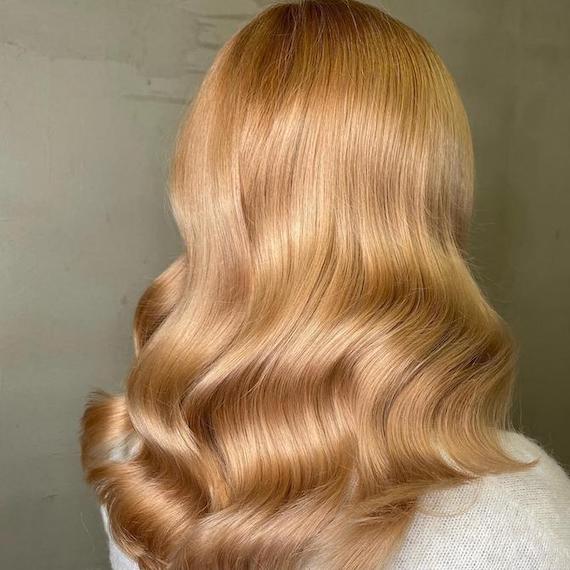 Hinterkopf einer Frau mit langem, goldkupferblondem Haar, kreiert mit Wella Professionals.