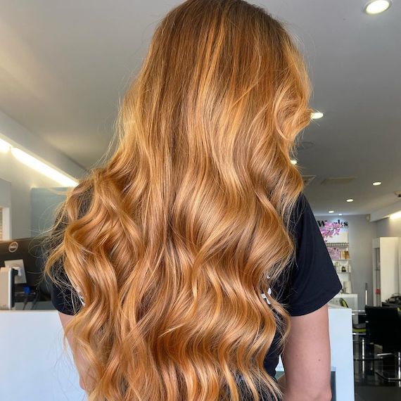 Model with glowy golden blonde hair, styled in a loose, polished wave.
