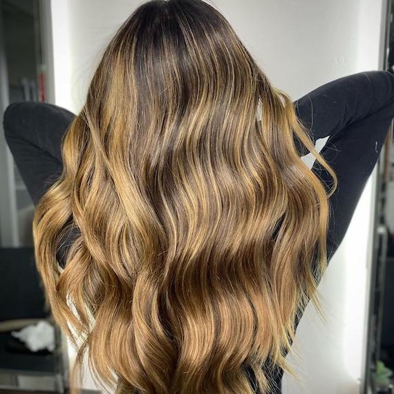 Model with long, dark brown hair featuring dark golden blonde highlights.