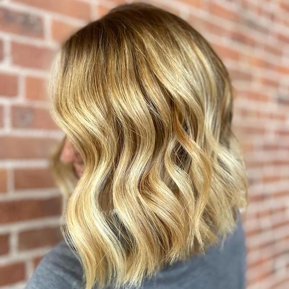 Model with shoulder-length, wavy hair in a bright golden blonde shade.