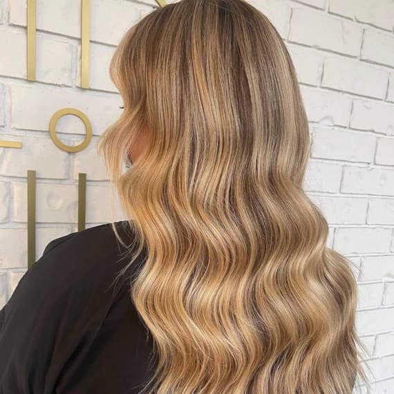 Model with long, dark blonde hair featuring chunky golden blonde highlights.