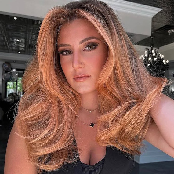 Model with long, golden peach blonde hair styled in a glossy blow-dry.