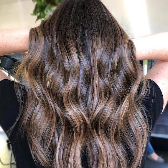 Hinterkopf einer Frau mit langem, gewelltem, braunem Haar und Balayage, kreiert mit Wella Professionals.