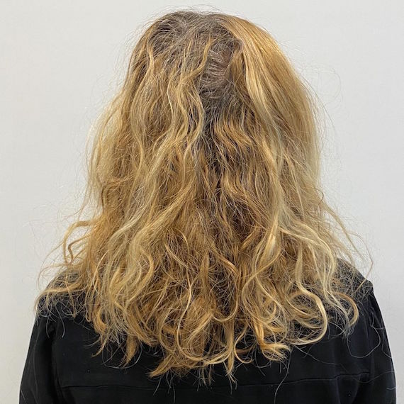 Photo of wavy blonde hair with gray roots.