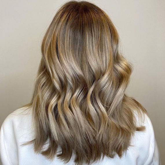 Back of a woman’s head with mid-length, glowy, dark blonde hair, created using Wella Professionals.
