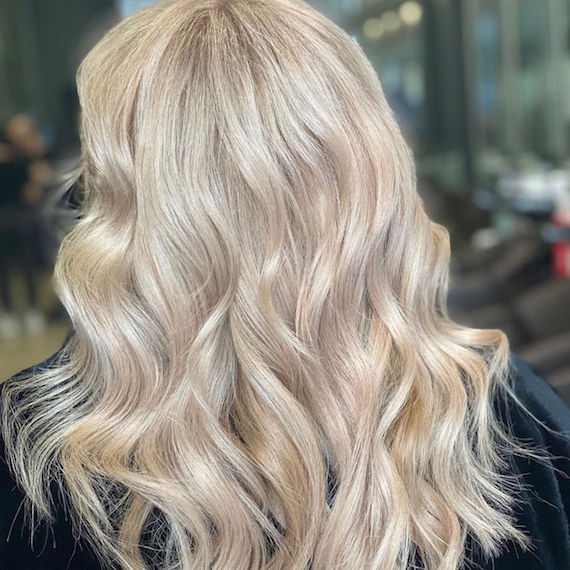Back of a woman’s head with long, wavy, platinum blonde hair, created using Wella Professionals.